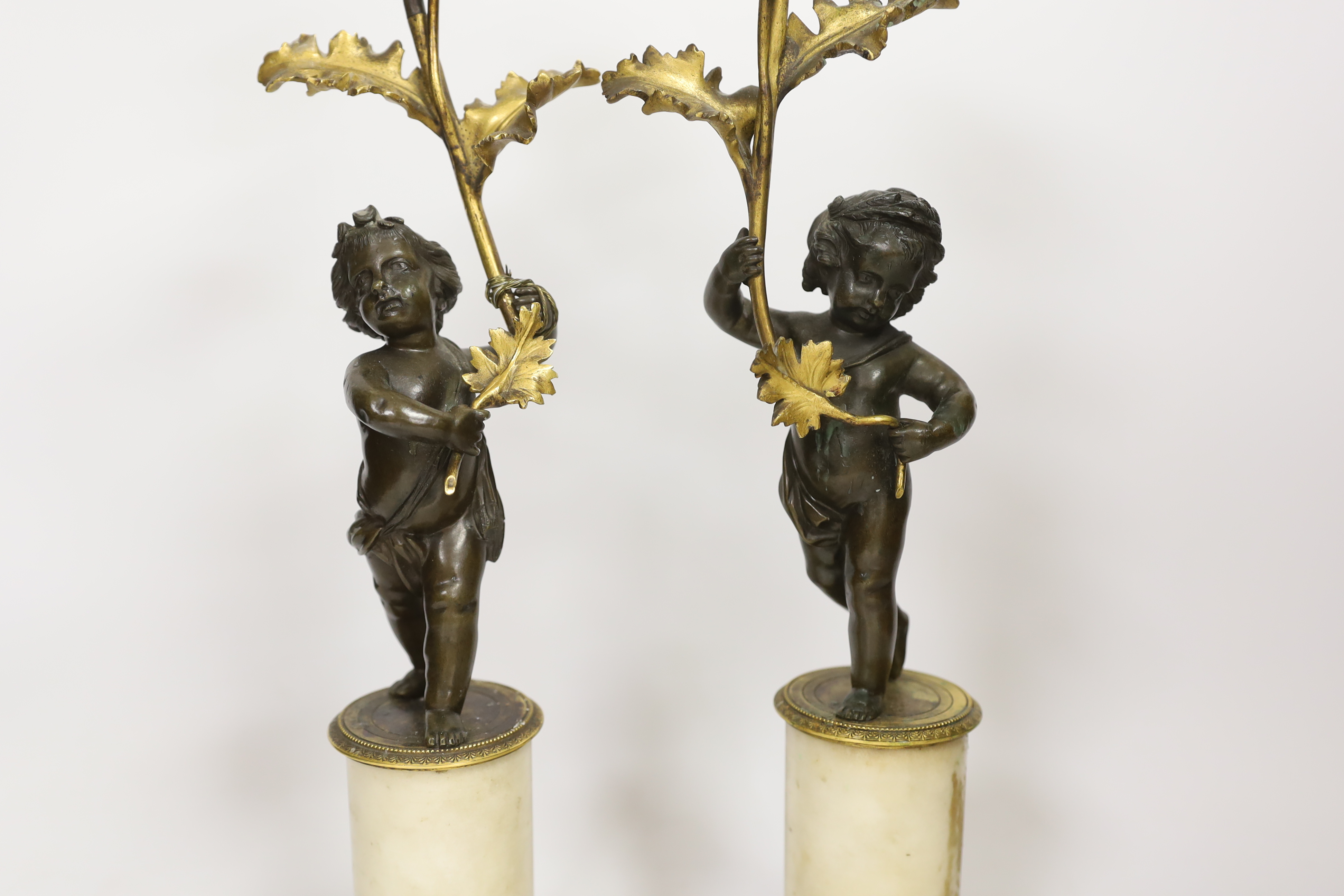 A pair of Regency bronze and ormolu amorini candlesticks, with white marble plinths, 40cm